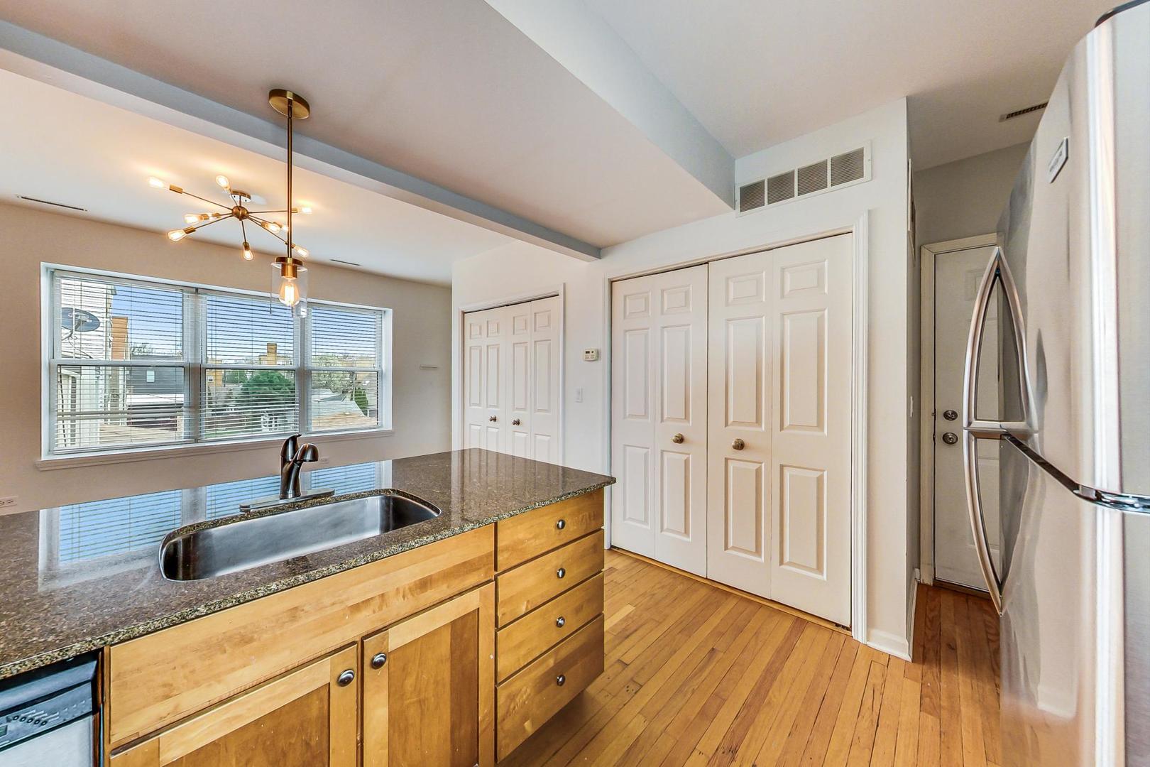 4017 North Troy Street, Unit 2W Chicago, IL 60618 - Photo 9 of 18 a kitchen with stainless steel appliances granite countertop a sink window and wooden floor