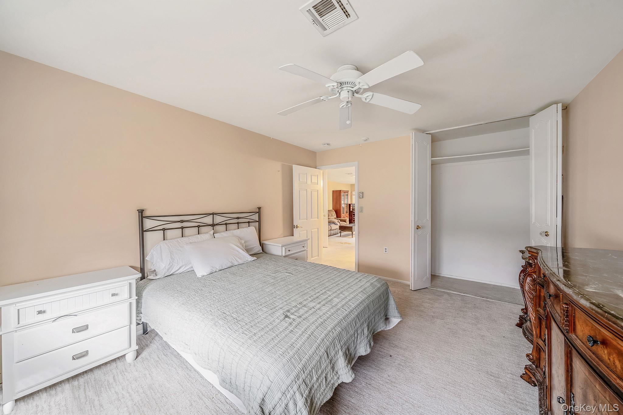 116 B Exmore Court Ridge, NY 11961 - Photo 17 of 19 a bedroom with a bed and a chandelier