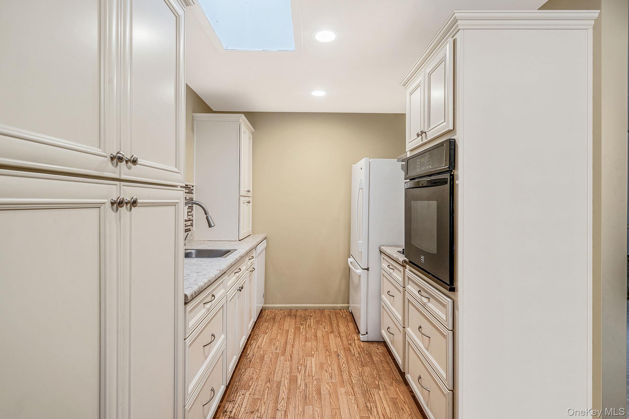 116 B Exmore Court Ridge, NY 11961 - Photo 10 of 19 a kitchen with white cabinets and stainless steel appliances