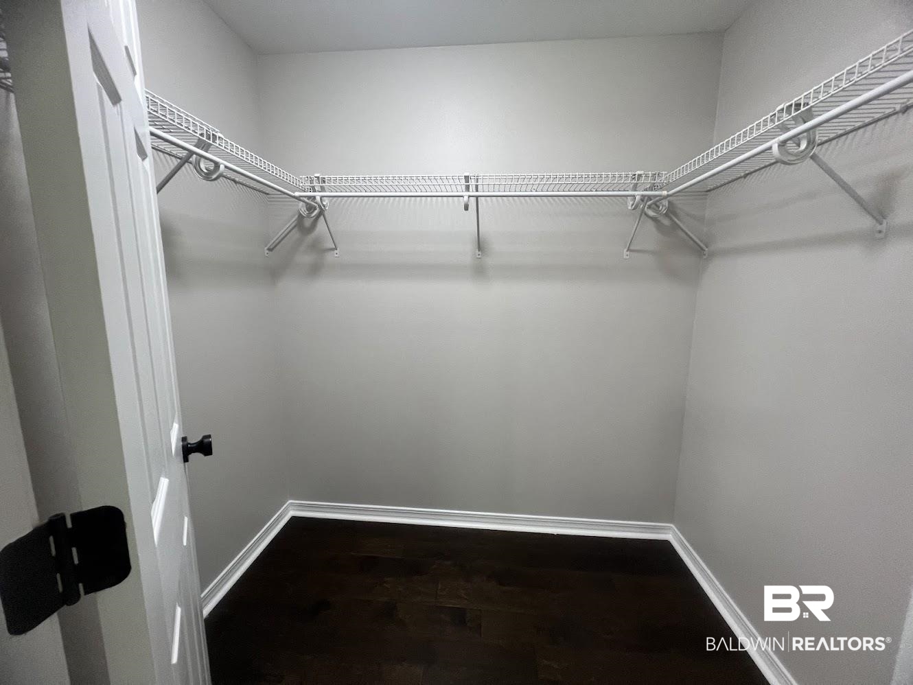 266 Ridgewood Drive Daphne, AL 36526 - Photo 16 of 34 Walk-in closet featuring L-shaped wire shelving, a hanging rod, light gray wall paint, white trim, and wood-finish flooring