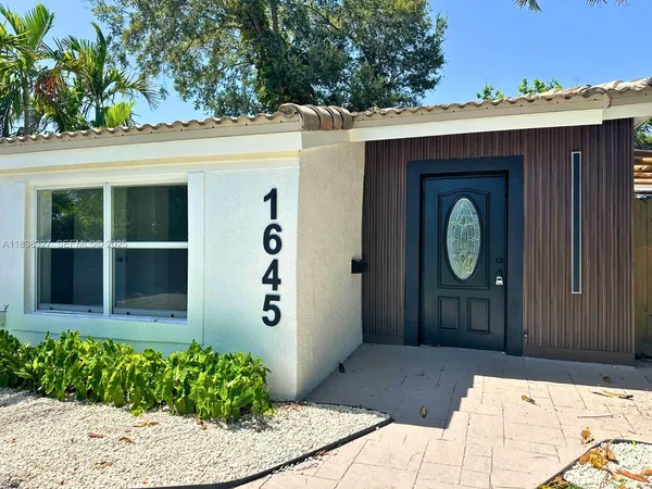 a front view of a house with a yard and potted plants