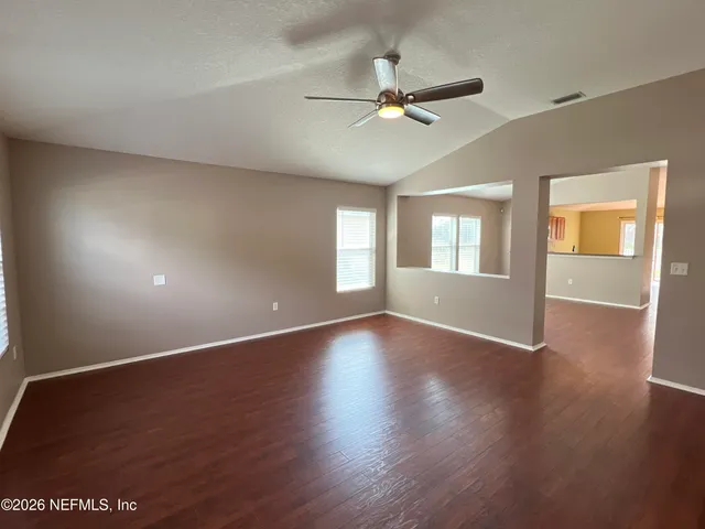 a view of an empty room with wooden floor and a window