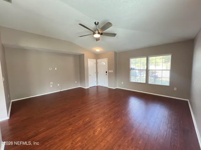 an empty room with wooden floor and windows
