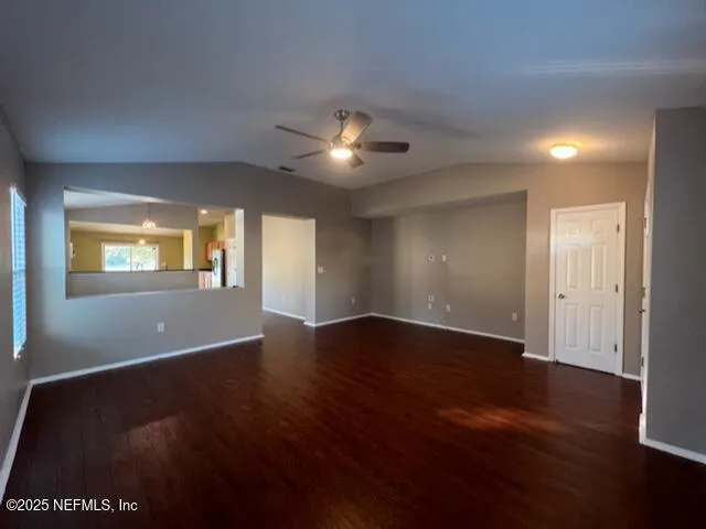 an empty room with wooden floor chandelier and windows