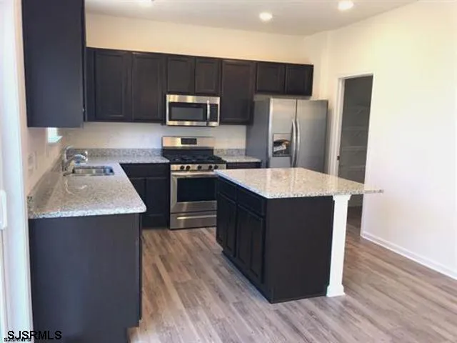 a kitchen with stainless steel appliances granite countertop wooden cabinets a refrigerator and a stove