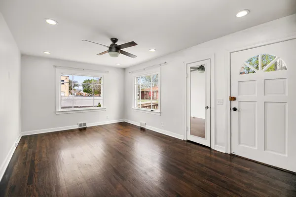 a view of an empty room with a window and wooden floor