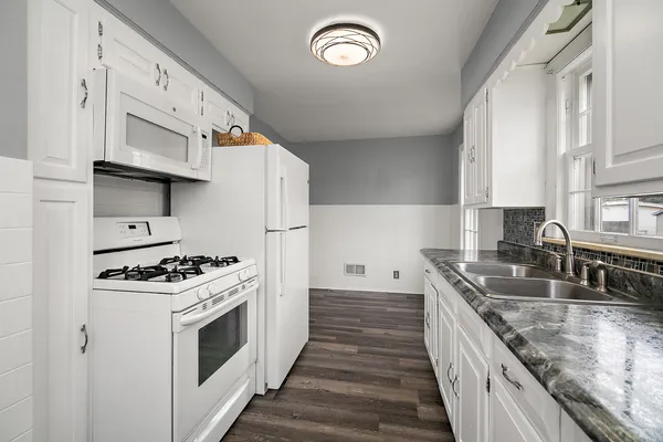 a kitchen with granite countertop a sink stove and cabinets