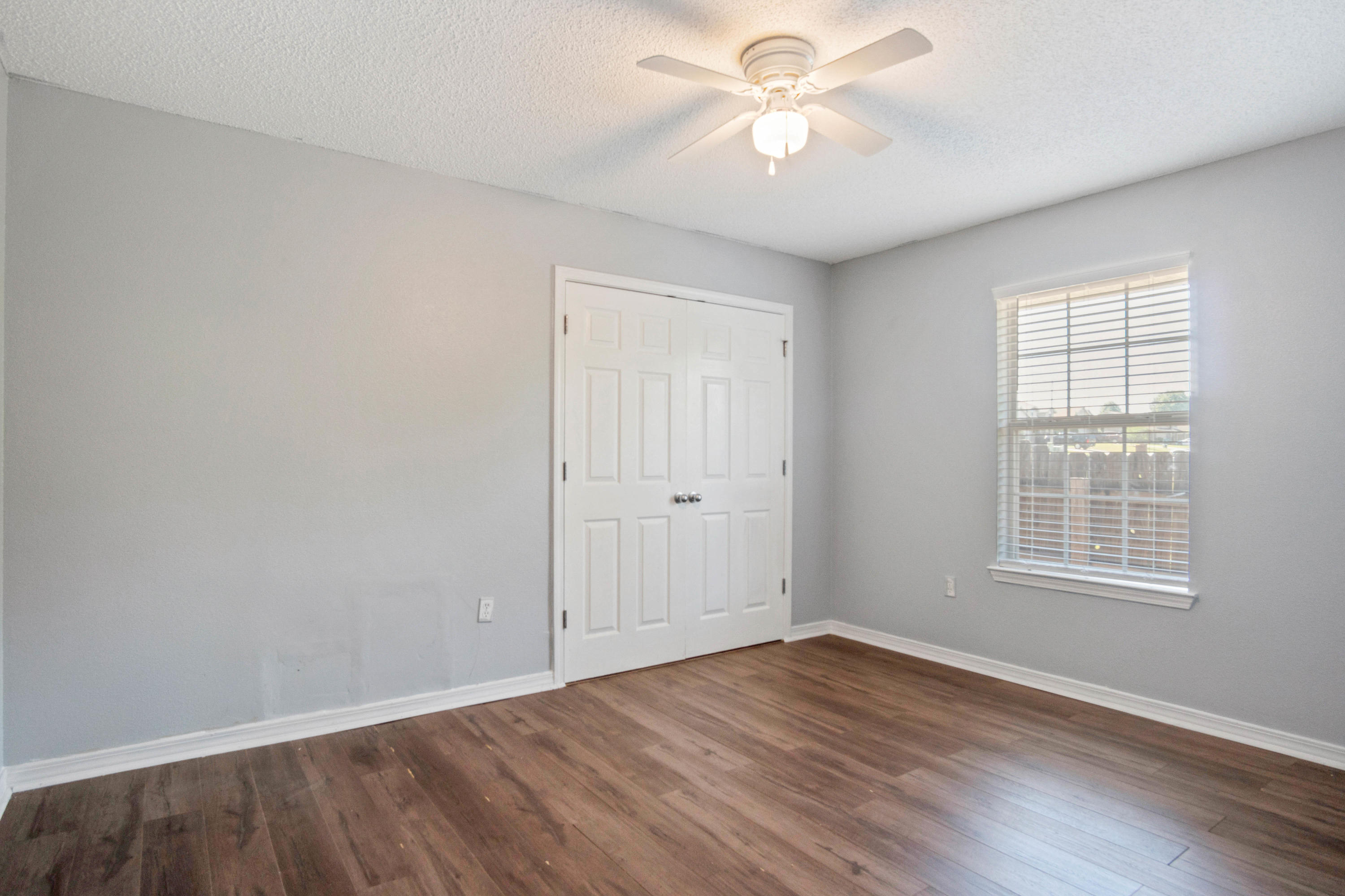 427 Triton Street Crestview, FL 32536 - Photo 18 of 32 an empty room with wooden floor ceiling fan and windows