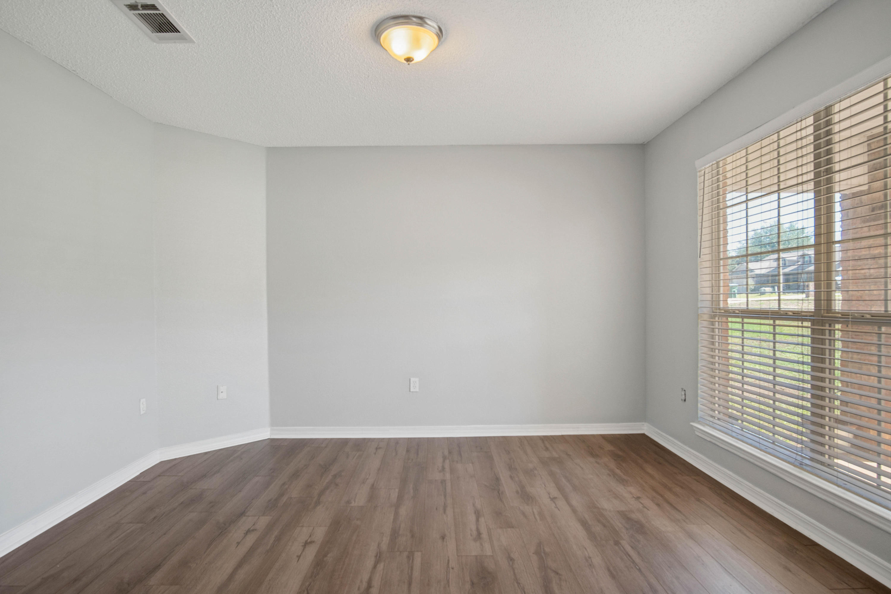 427 Triton Street Crestview, FL 32536 - Photo 7 of 32 a view of an empty room with wooden floor and a window