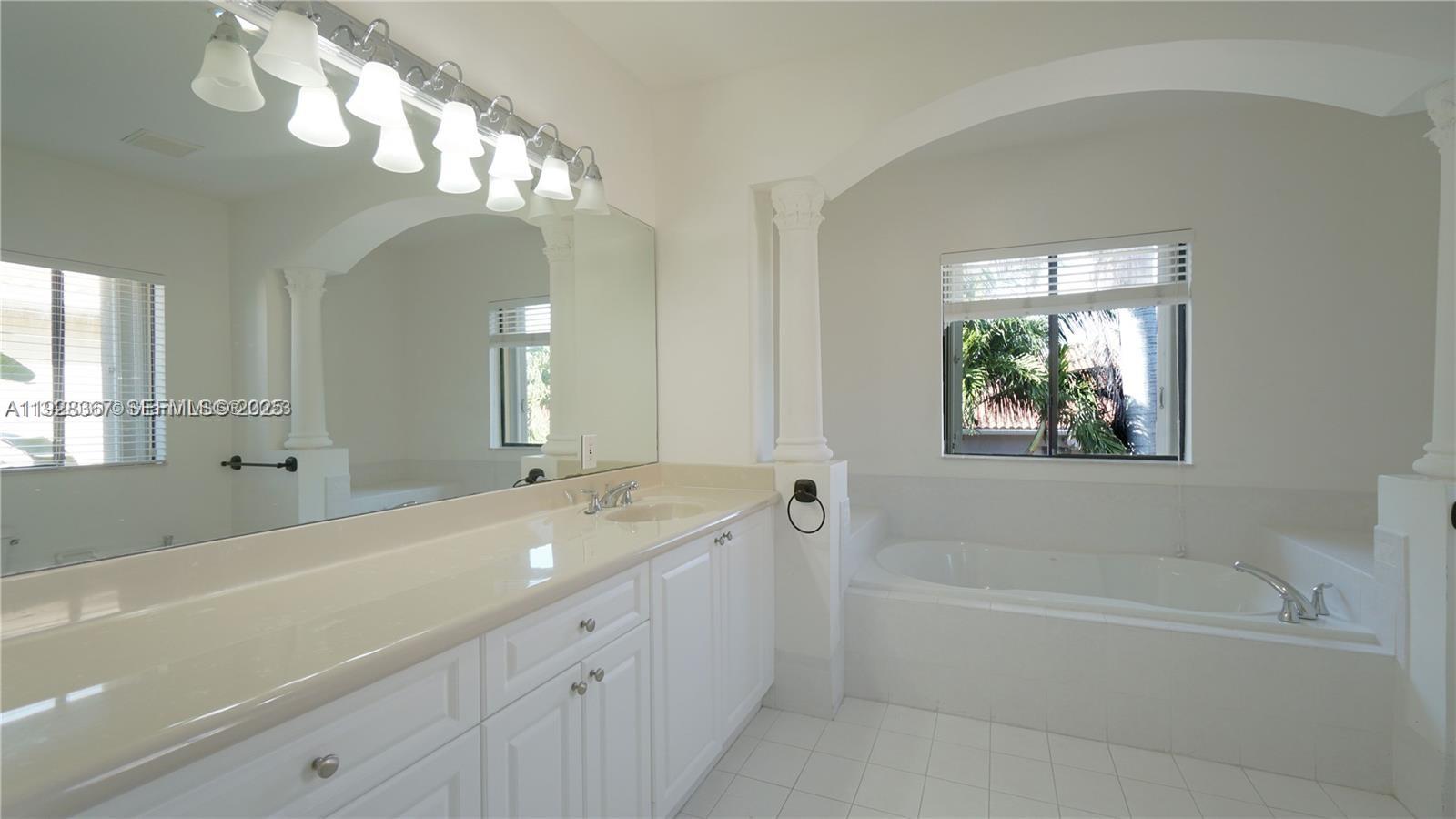 7507 Southwest 189th Street, Unit 7507 Cutler Bay, FL 33157 - Photo 17 of 28 a spacious bathroom with a bathtub a double vanity sink a vanity a lamp and a chandelier