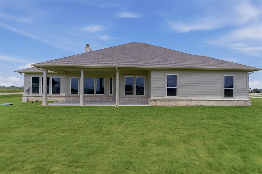 2204 Continent Court Krum, TX 76249 - Photo 27 of 28 Rear exterior featuring a covered patio, multiple large windows, light-colored siding, a stone-accented foundation, and a shingled roof