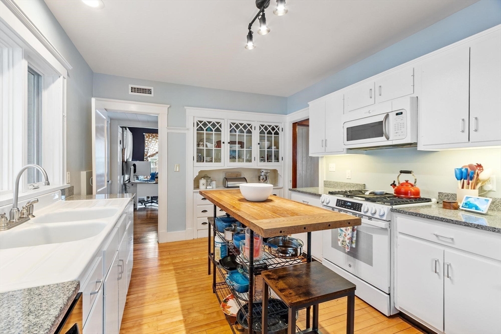 20 Shattuck Street Littleton, MA 01460 - Photo 20 of 41 a kitchen with a stove a sink dishwasher a dining table and chairs with wooden floor