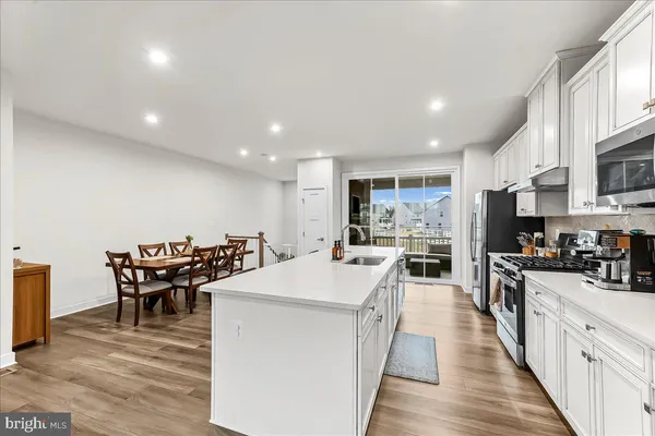 a large kitchen with kitchen island a dining table chairs and a wooden floor