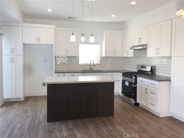a kitchen with granite countertop a sink a stove and cabinets
