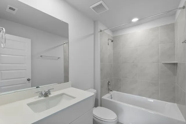 a bathroom with a bathtub shower sink vanity mirror and toilet