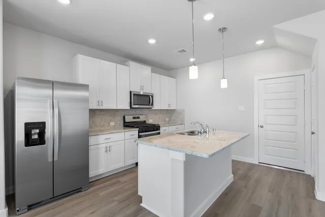 a kitchen with a sink a stove a refrigerator and white cabinets