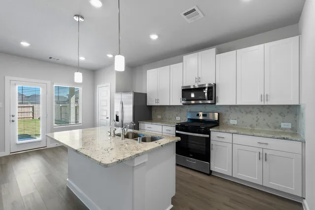 a kitchen with stainless steel appliances granite countertop a sink a stove and a wooden floors