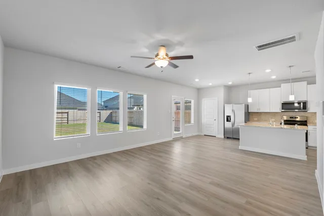 a view of an empty room with a kitchen and wooden floor