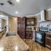 a large kitchen with stainless steel appliances granite countertop a sink stove and refrigerator