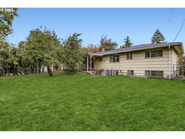 a view of a house with a big yard and large tree