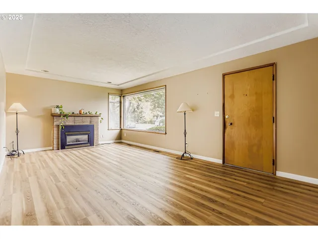 a view of an empty room with a window and wooden floor