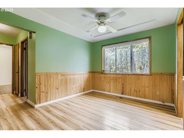 an empty room with wooden floor fan and windows