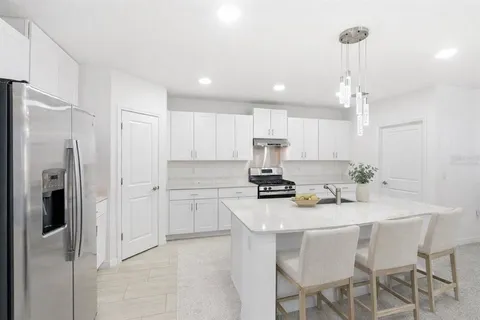 a kitchen with stainless steel appliances a refrigerator a sink dishwasher a stove a dining table and chairs with wooden floor