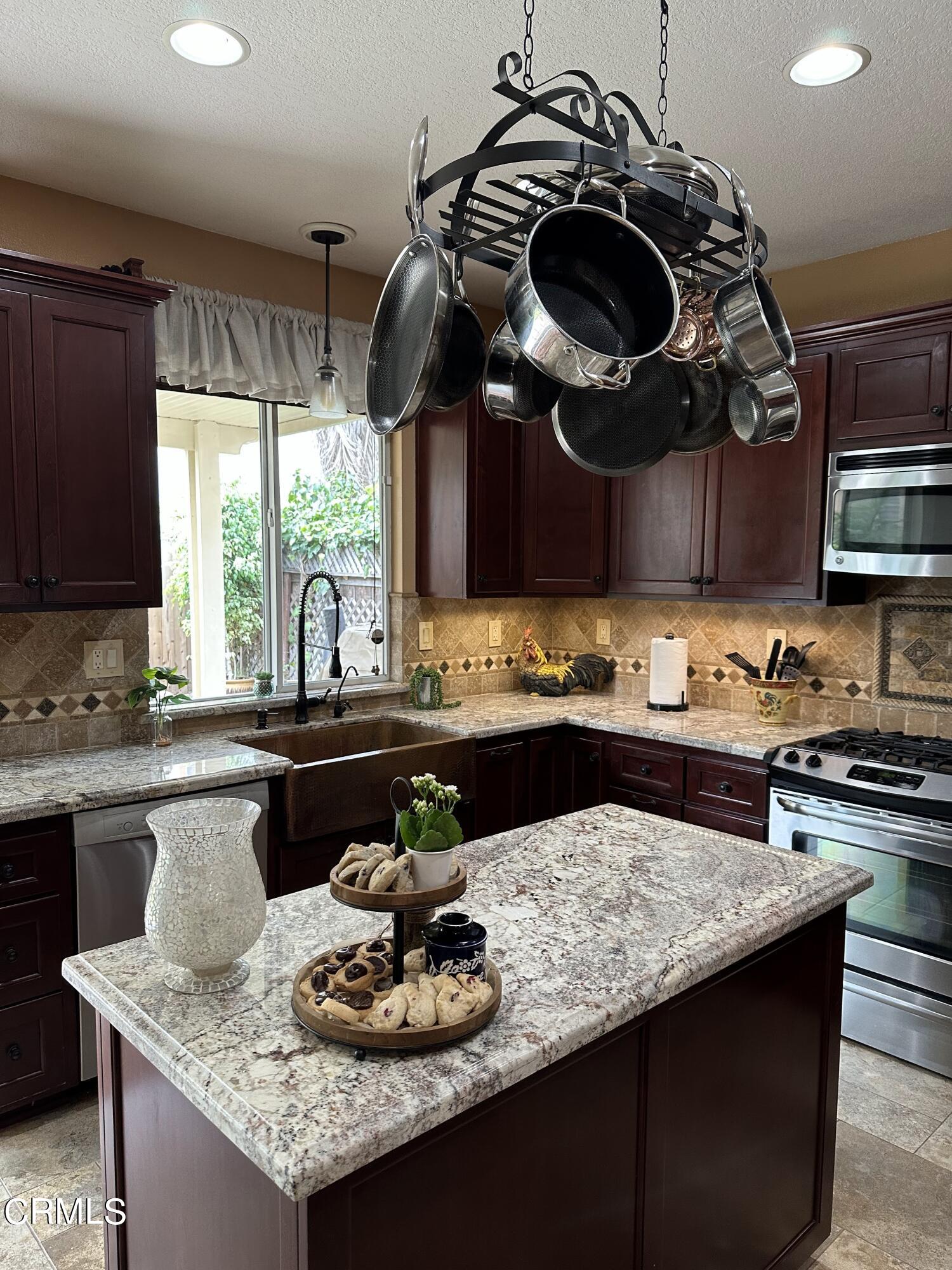 803 Noontide Way Oxnard, CA 93035 - Photo 7 of 26 a kitchen with a stove a microwave and wooden cabinets