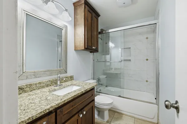 a bathroom with a granite countertop sink toilet and shower