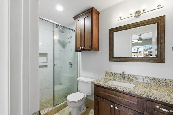 a bathroom with a granite countertop sink toilet and shower