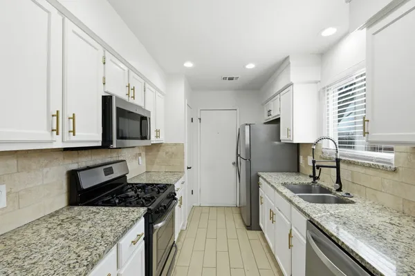 a kitchen with stainless steel appliances granite countertop a sink stove and refrigerator
