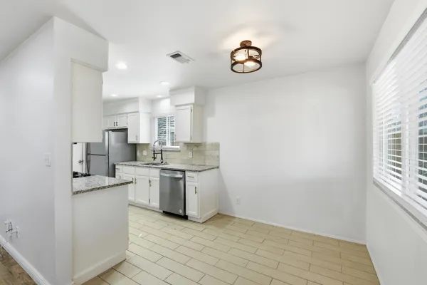 a view of a kitchen with a sink dishwasher a stove top oven a clock and a window