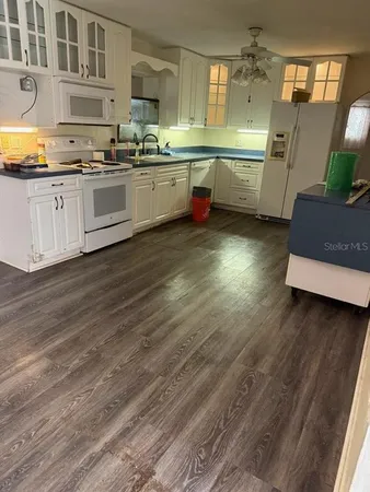 a kitchen with granite countertop a sink cabinets and wooden floor
