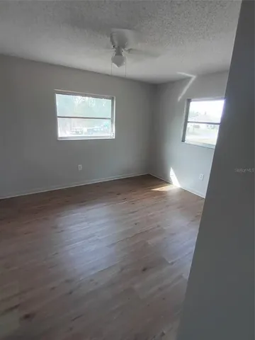 an empty room with wooden floor windows and closet