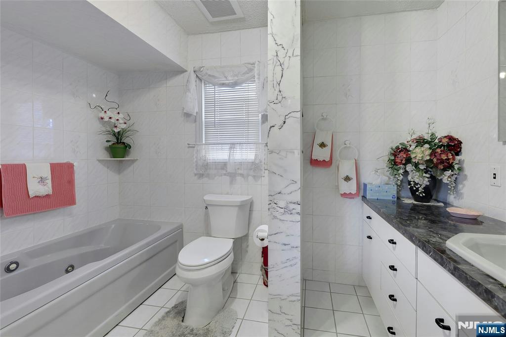 4 Highfield Court Wayne, NJ 07470 - Photo 16 of 49 a bathroom with a granite countertop toilet a sink and a bathtub