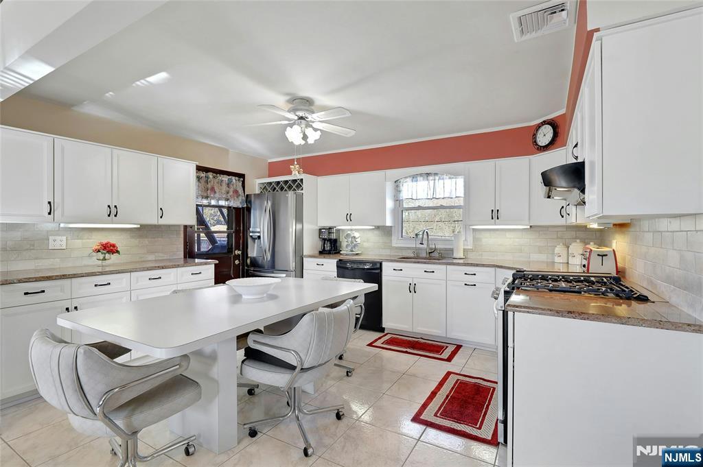 4 Highfield Court Wayne, NJ 07470 - Photo 9 of 49 a kitchen with a stove a refrigerator and white cabinets