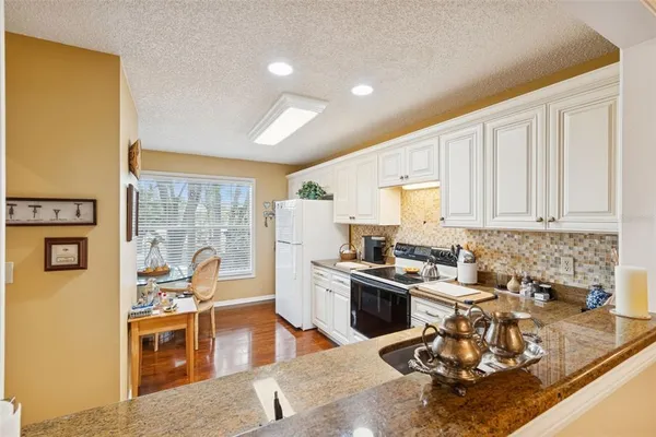 a kitchen with a sink granite counter tops and a view of living room