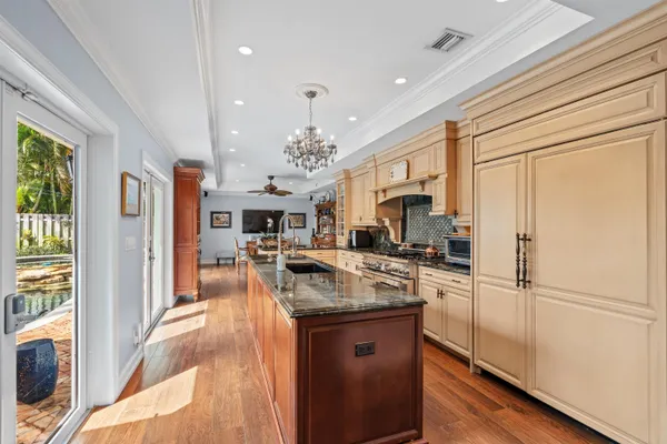 a kitchen with granite countertop a refrigerator a sink dishwasher a oven with a dining table and chairs