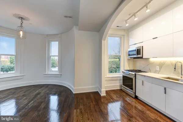 a kitchen with stainless steel appliances granite countertop a sink a stove a microwave and wooden floors