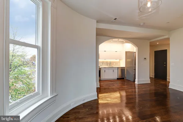 a view of a hallway with wooden floor and a kitchen