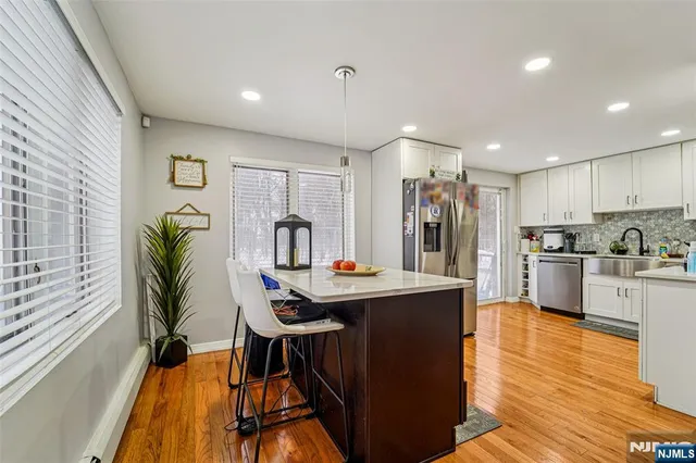 a kitchen with kitchen island a counter top space a sink stainless steel appliances and cabinets