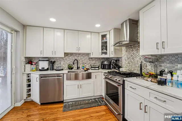 a kitchen with stainless steel appliances granite countertop a stove a sink and white cabinets