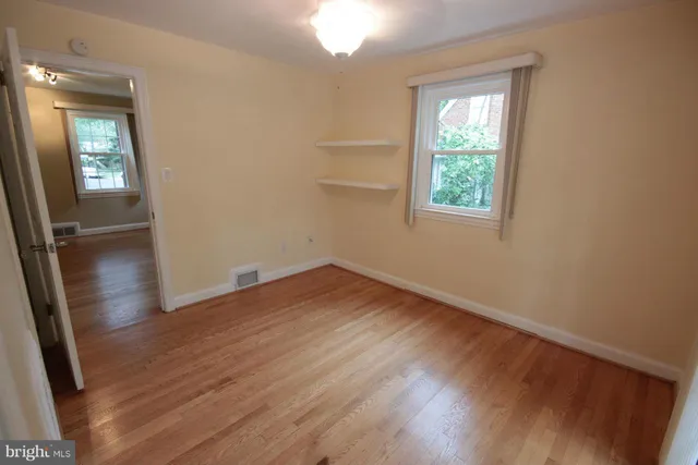 an empty room with wooden floor and a window