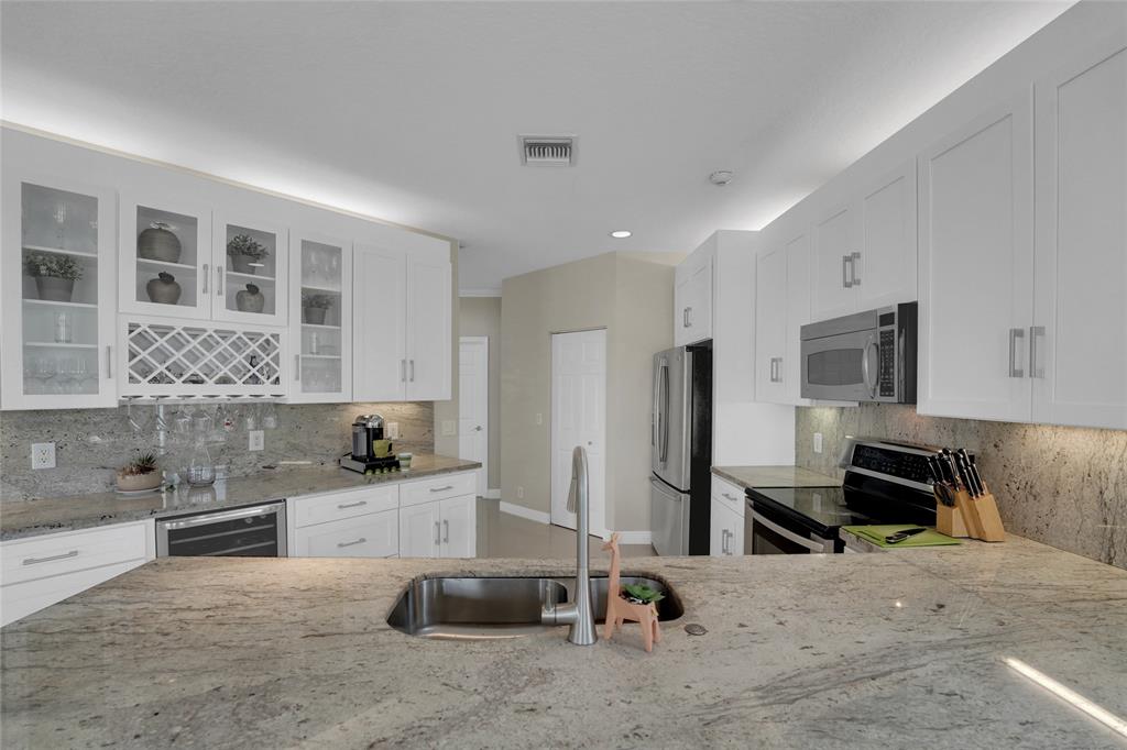 22280 Tupelo Place Boca Raton, FL 33428 - Photo 23 of 53 a kitchen with stainless steel appliances kitchen island granite countertop a stove and a sink