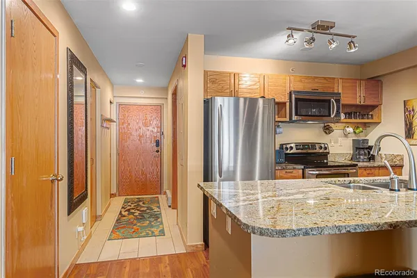 a kitchen with stainless steel appliances granite countertop a refrigerator a stove and a sink