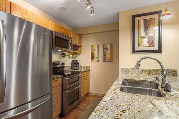 a kitchen with stainless steel appliances granite countertop a refrigerator stove top oven and sink