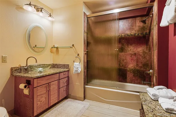 a bathroom with a granite countertop sink a toilet and shower