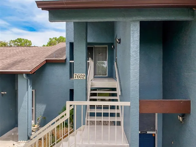 a view of a hallway with wooden floor and a bathroom