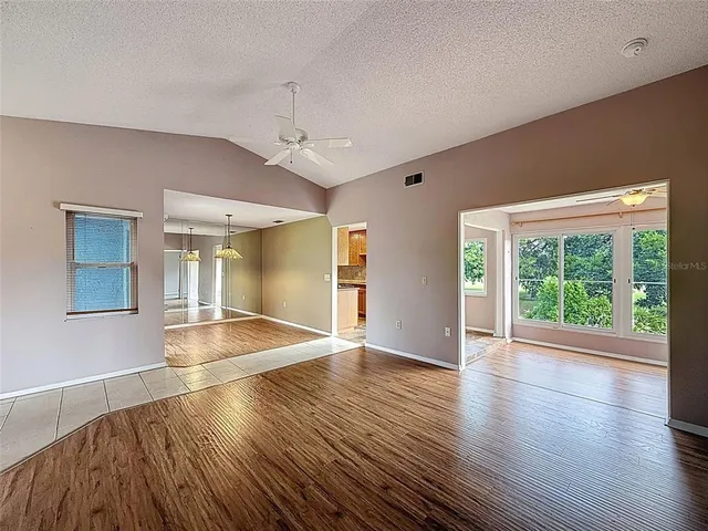 a view of an empty room with window wooden floor and a kitchen