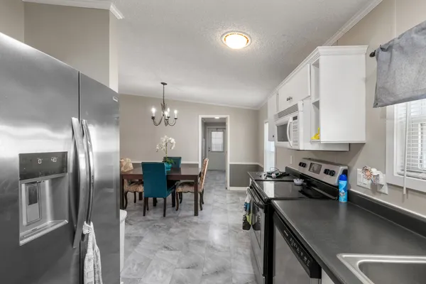 a kitchen with stainless steel appliances granite countertop a sink refrigerator and chairs